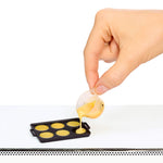 Hand pouring batter into a mini mold on a white background