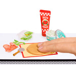 Playset with mini pizza ingredients and a hand interacting with them on a white background.