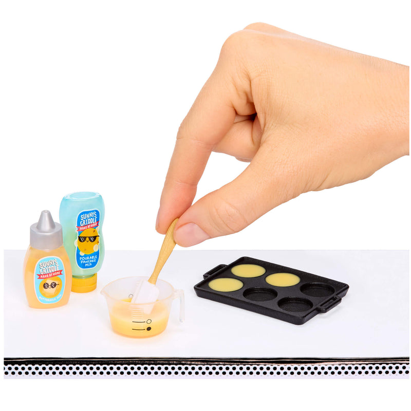 Hand using a wooden spoon to mix yellow substance in a small container with bottles and a mold in the background.