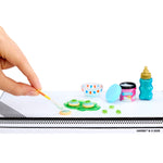 Miniature scene with a hand holding a brush, colorful candies, and a bottle on a white background.