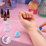 Hand applying perfume to wrist on a pink surface with 'Real Scents!' branding.