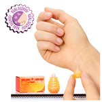 Hand holding a small orange bottle with a cap, next to 'Real Scents' packaging on a white background.