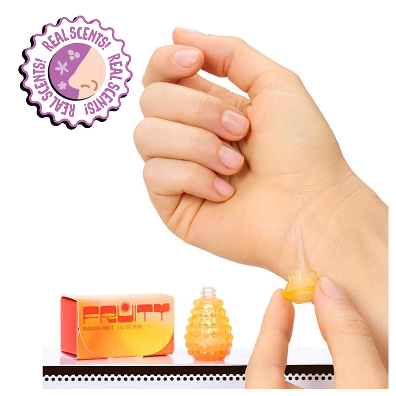Hand holding a small orange bottle with a cap, next to 'Real Scents' packaging on a white background.