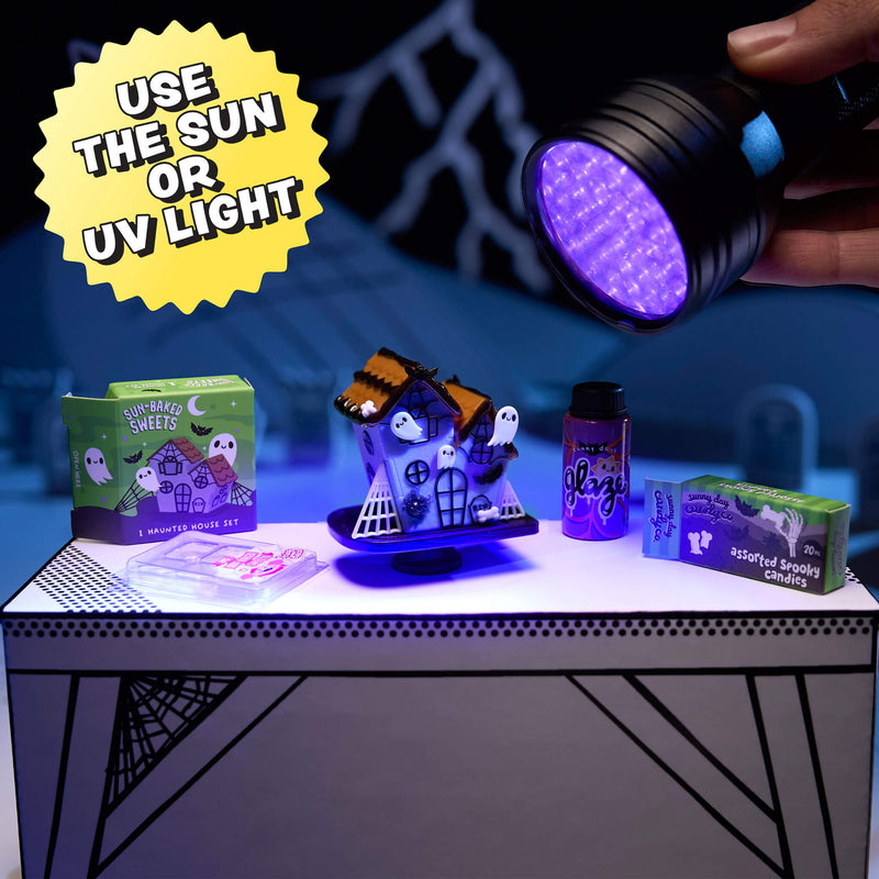 Halloween-themed items including a haunted house, boxes, and a UV light on a table.