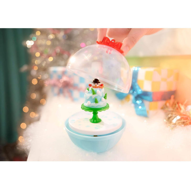 Small snow globe with a snowman inside, held by a hand against a blurred festive background.