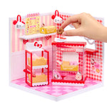 Hello Kitty-themed mini playset with a hand interacting with it on a white background