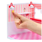Small Hello Kitty-themed miniature playset with a hand holding a small yellow object.