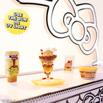 Mini ice cream sundae with caramel syrup, whipped cream, and a mini container of ice cream on a table.