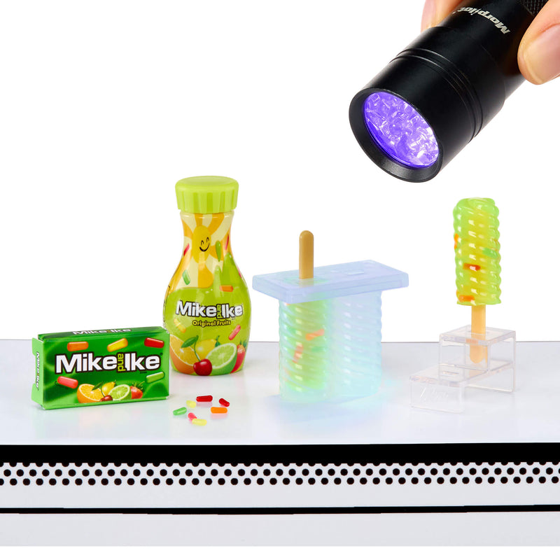 Mike & Ike candy with a bottle, popsicle mold, and a flashlight on a white background