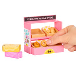 Pink toy bakery set with donuts and a hand interacting with it on a white background