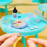 Miniature table setup with vinegar bottle, ice cubes, and a small bowl on a bright yellow background.