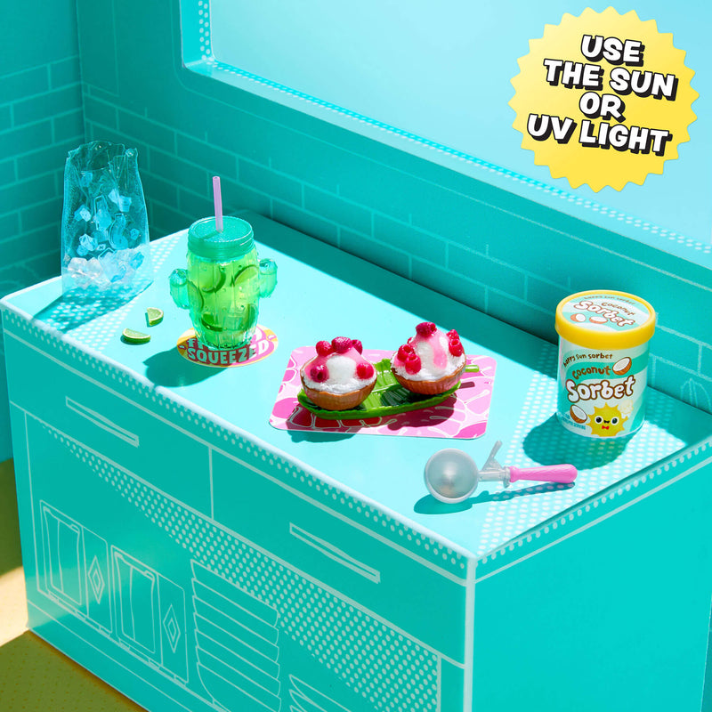 Toy kitchen set with a green cup, ice cream, and a container labeled 'Sorbet' on a teal countertop.