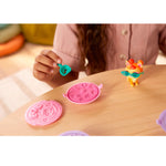 Colorful sand and pet on a wooden surface with a child's hand holding one of them.