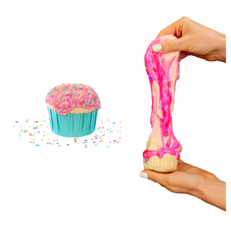 Slime being stretched by a hand next to a cupcake toy with sprinkles on a white background
