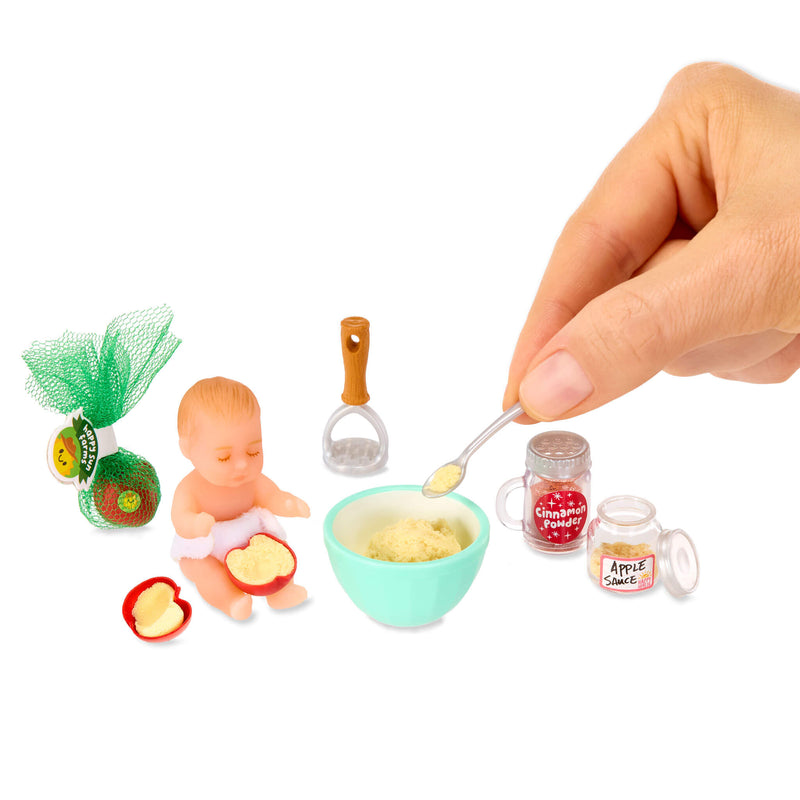 Miniature baby with mini food items and a hand holding a spoon over a bowl on a white background