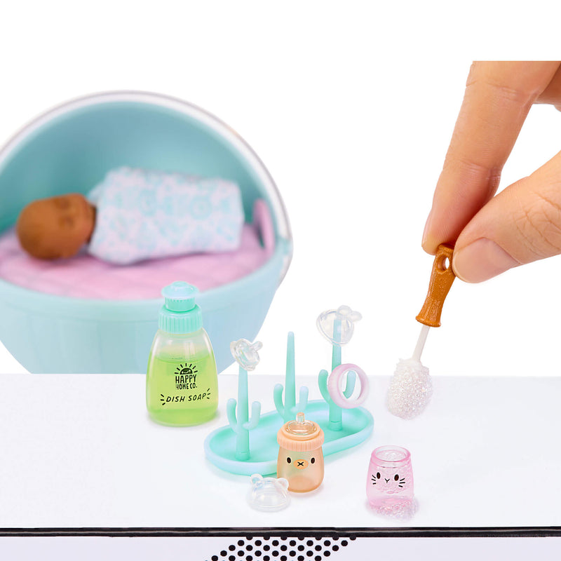 Miniature cleaning set with a hand using a brush, including a sink, bottles, and other cleaning tools on a white background.
