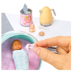 Miniature baby doll in a ball with feeding accessories on a white background