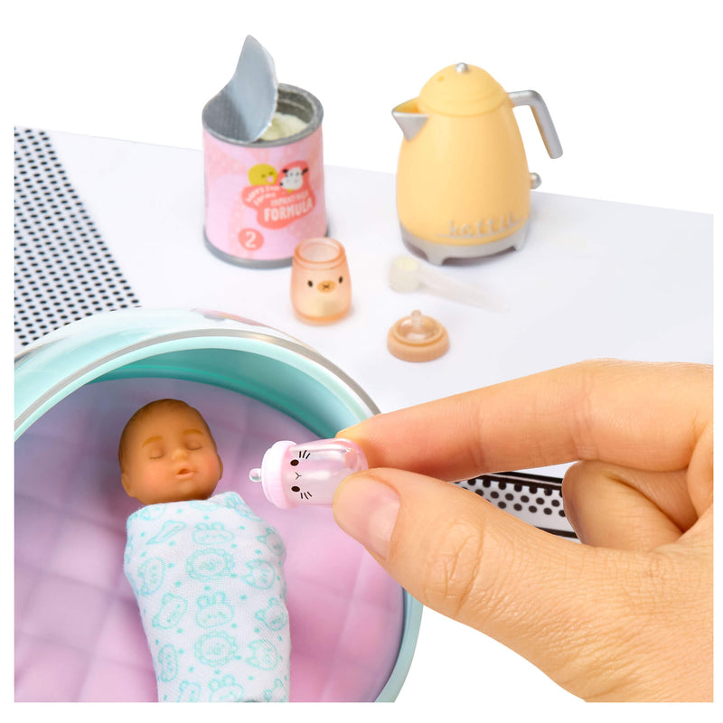 Miniature baby doll in a ball with feeding accessories on a white background