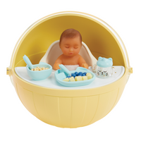 Darker skin baby in a yellow capsule with toys and a spoon on a white background