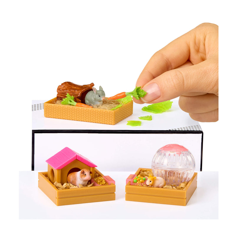 Miniature pet playset with a hand holding food above it, on a white background.