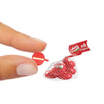 Miniature bag of Babybel cheese with a hand holding a small red circle, on a white background.