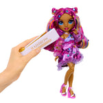Colorful doll with rainbow hair and bedazzling tool held by a hand against a white background