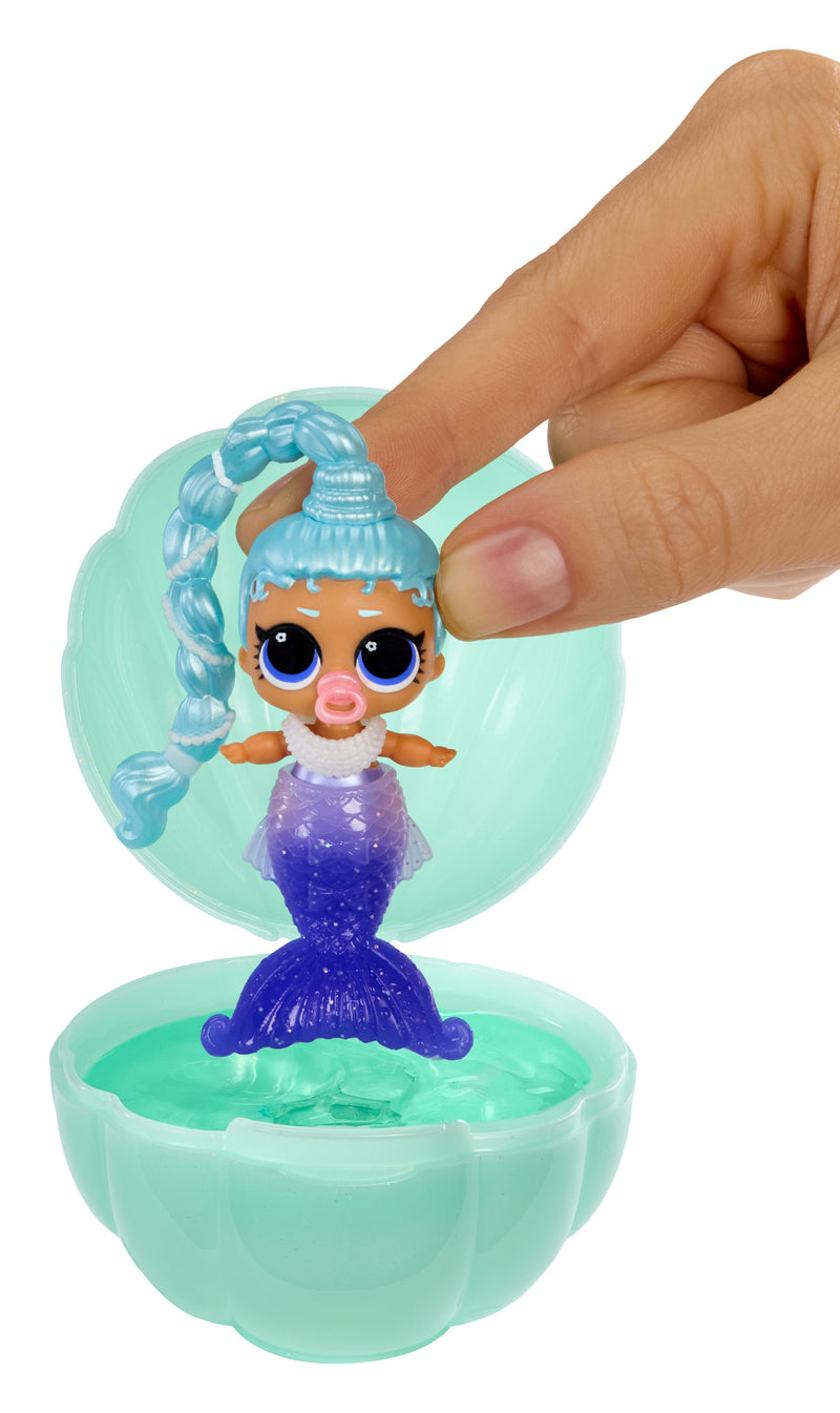 Mermaid toy figure in a small green shell with a hand lifting it.