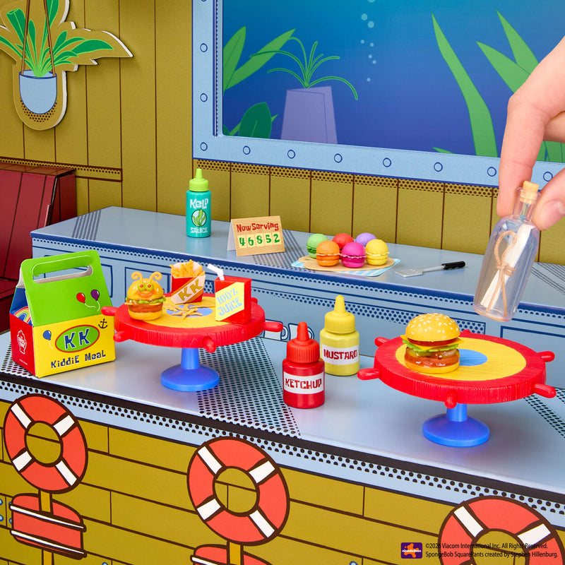 Toy kitchen set with toy hamburgers and condiments on a colorful playset.
