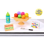 Miniature food items and accessories on a white surface with text and branding.