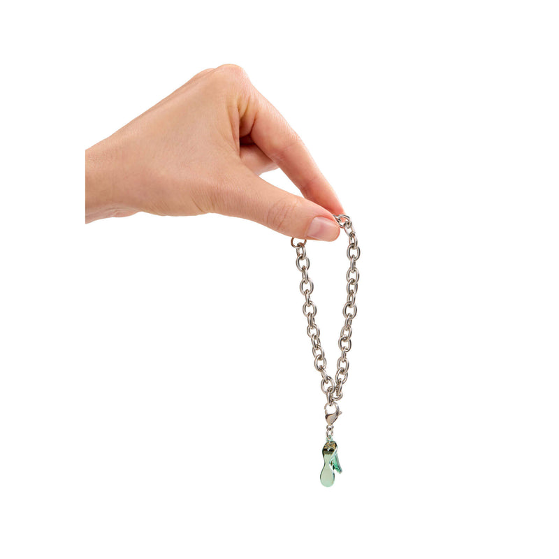 Hand holding a silver bracelet with green charm against a white background