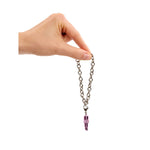 Hand holding a bracelet with a purple crystal pendant on a white background