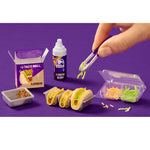 Miniature Taco Bell food set with hand adding toppings on a purple background