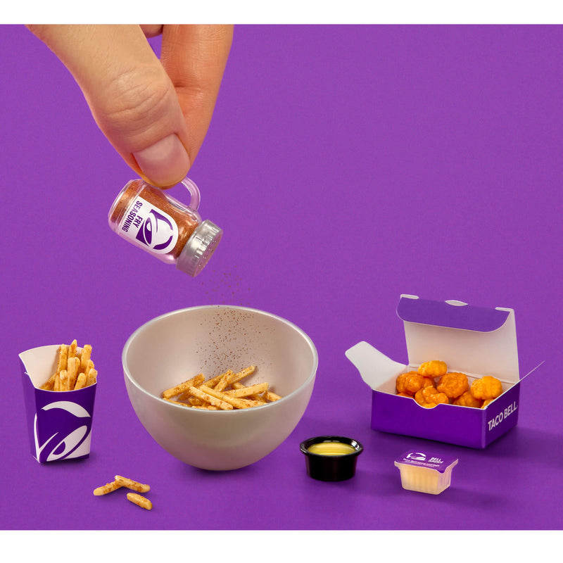 Taco Bell food items including a bowl of fries, a box of chicken nuggets, and a container of sauce on a purple background.