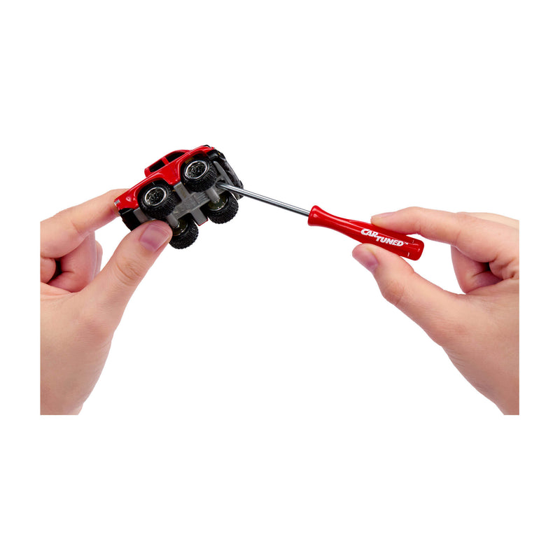 Two hands, right hand using a red screwdriver to connect the truck’s top and bottom, being held by left hand on a white background