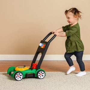 Girl playing inside with toy lawn mower