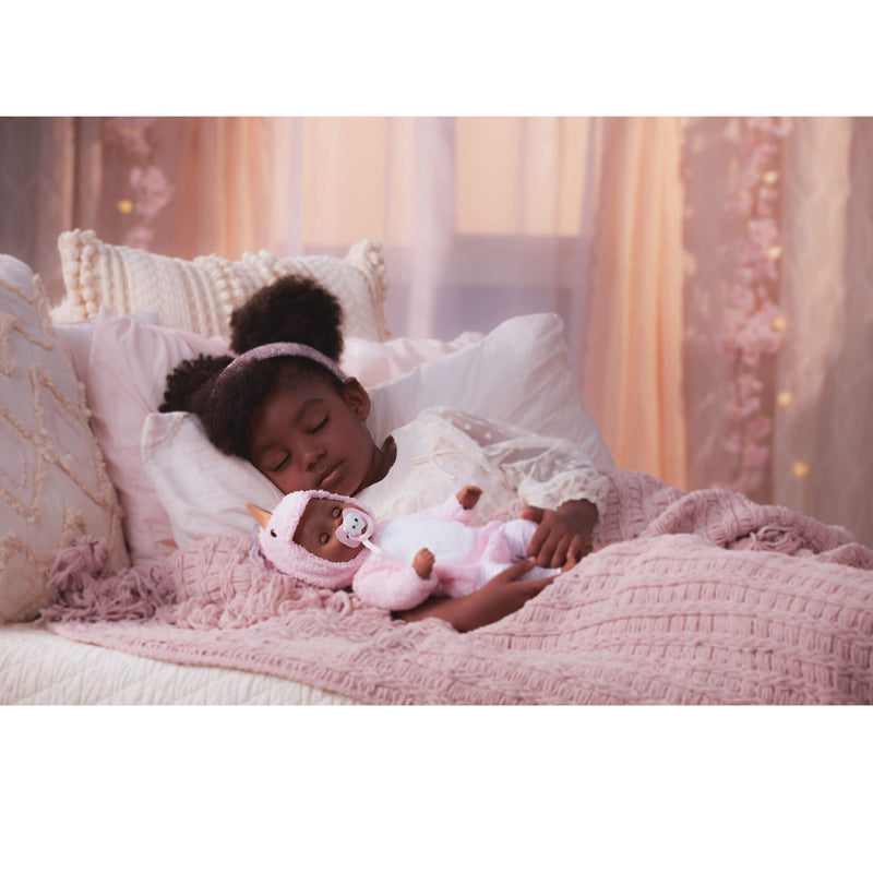 Child sleeping on a bed with Harper, surrounded by soft lighting and pink bedding.