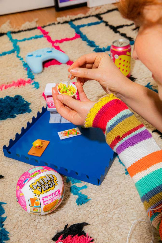 Child playing with a Miniverse toy on a colorful rug