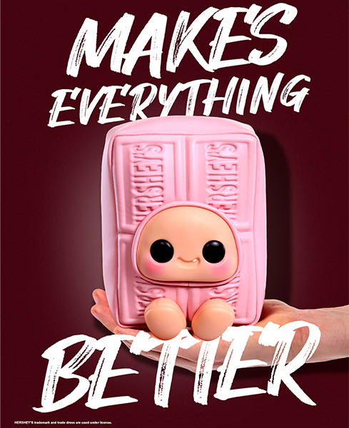 Pink Hershey's chocolate bar with a face, held by a hand, on a dark background with text 'Makes Everything Better'.