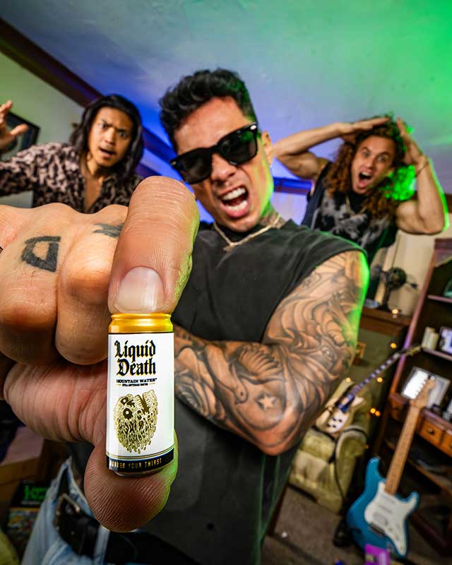 Person holding a 'Liquid Death' bottle with a lively background