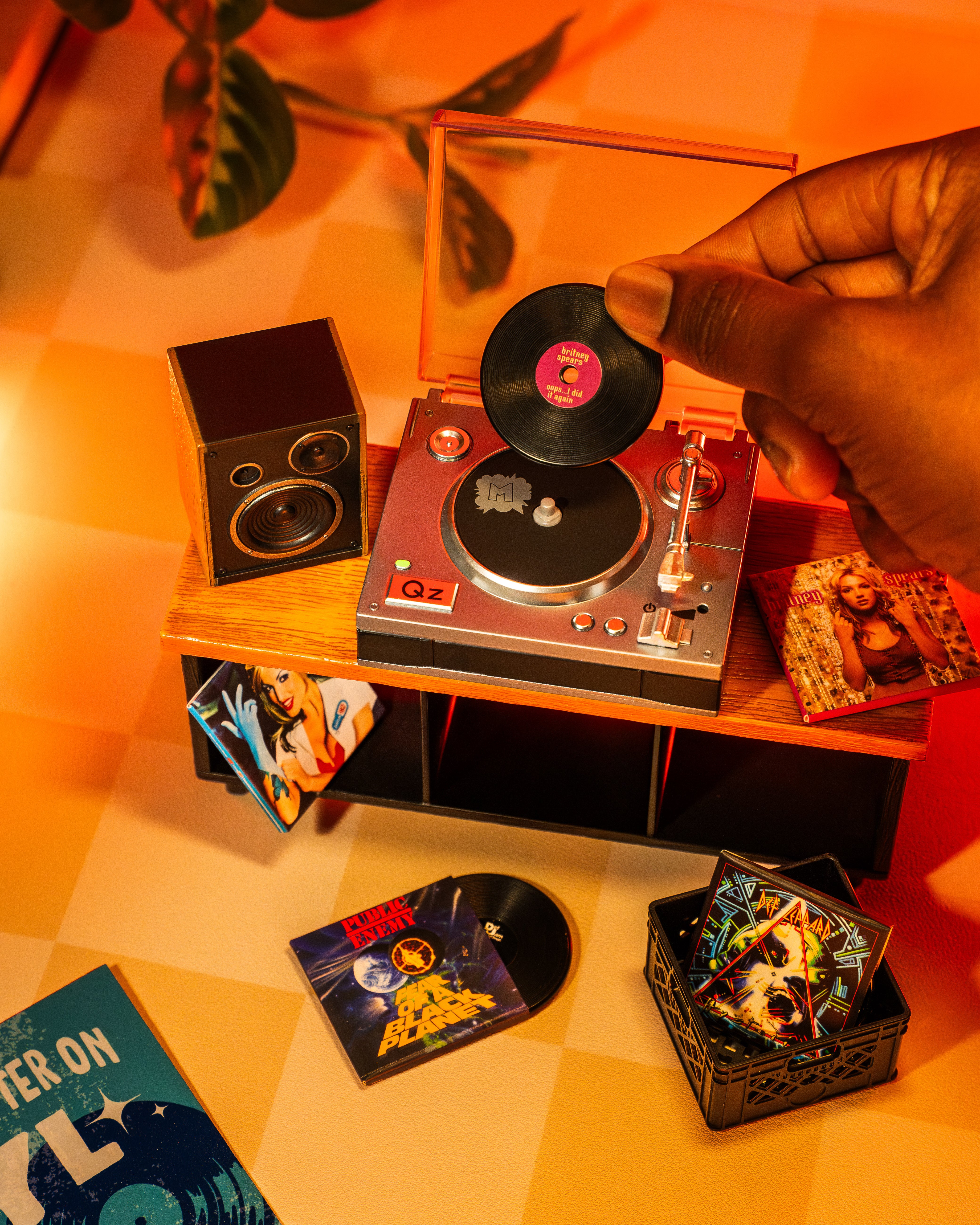 Person placing a vinyl record on a Miniverse turntable with a warm, orange-toned light.