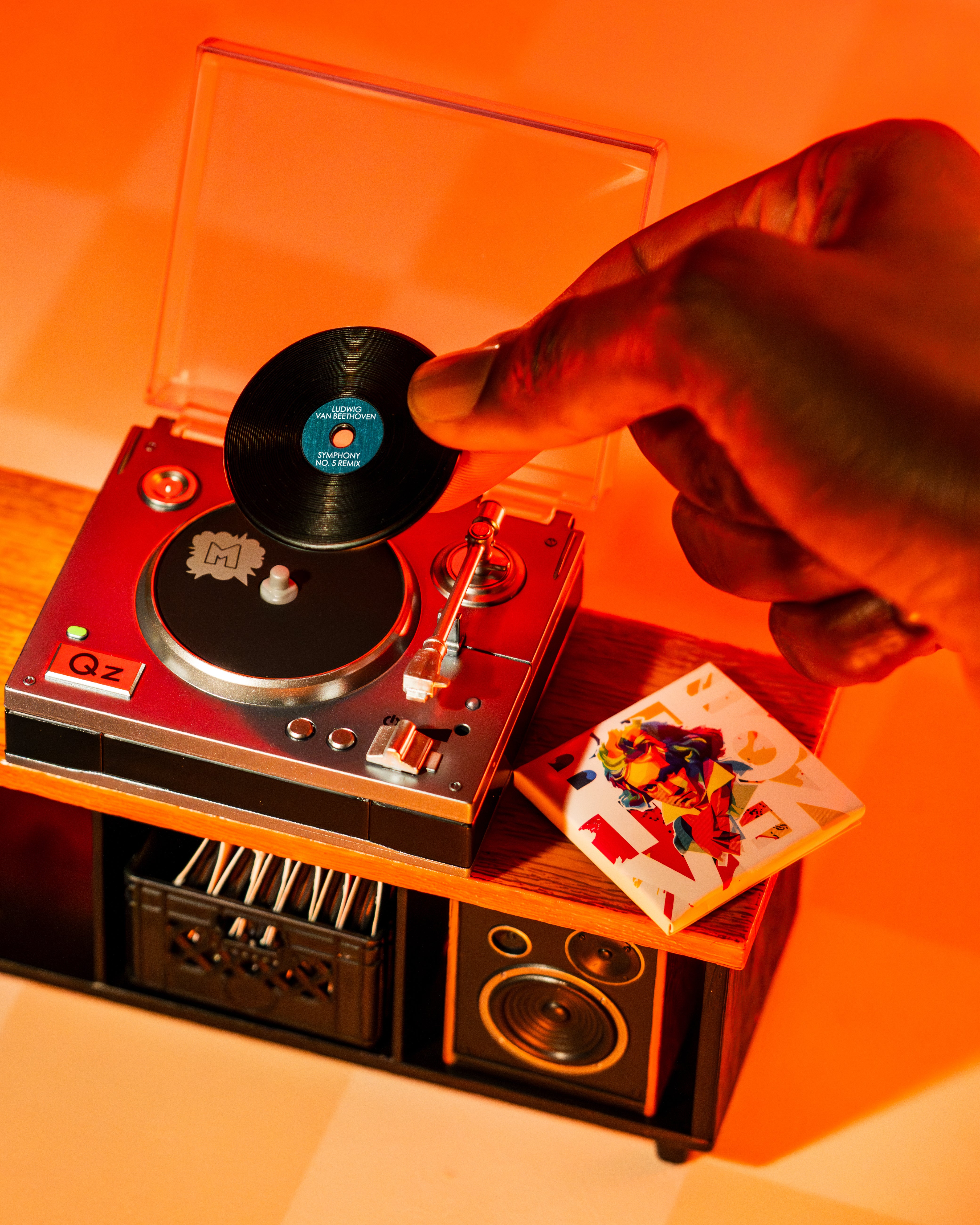 Person placing a vinyl record on a Miniverse turntable with an orange glow