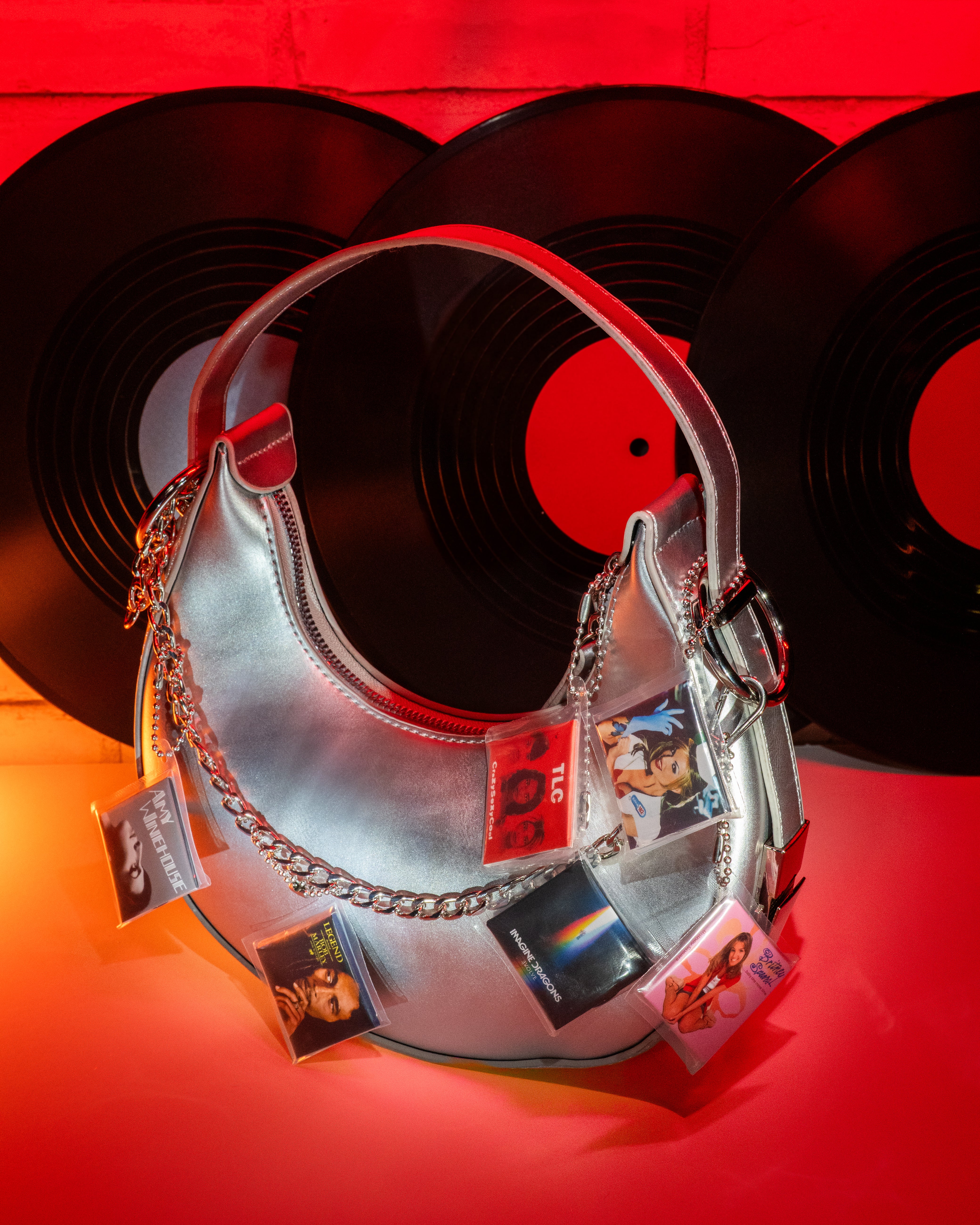 Metallic purse showing Miniverse albums on keychains in front of vinyl records on a red background