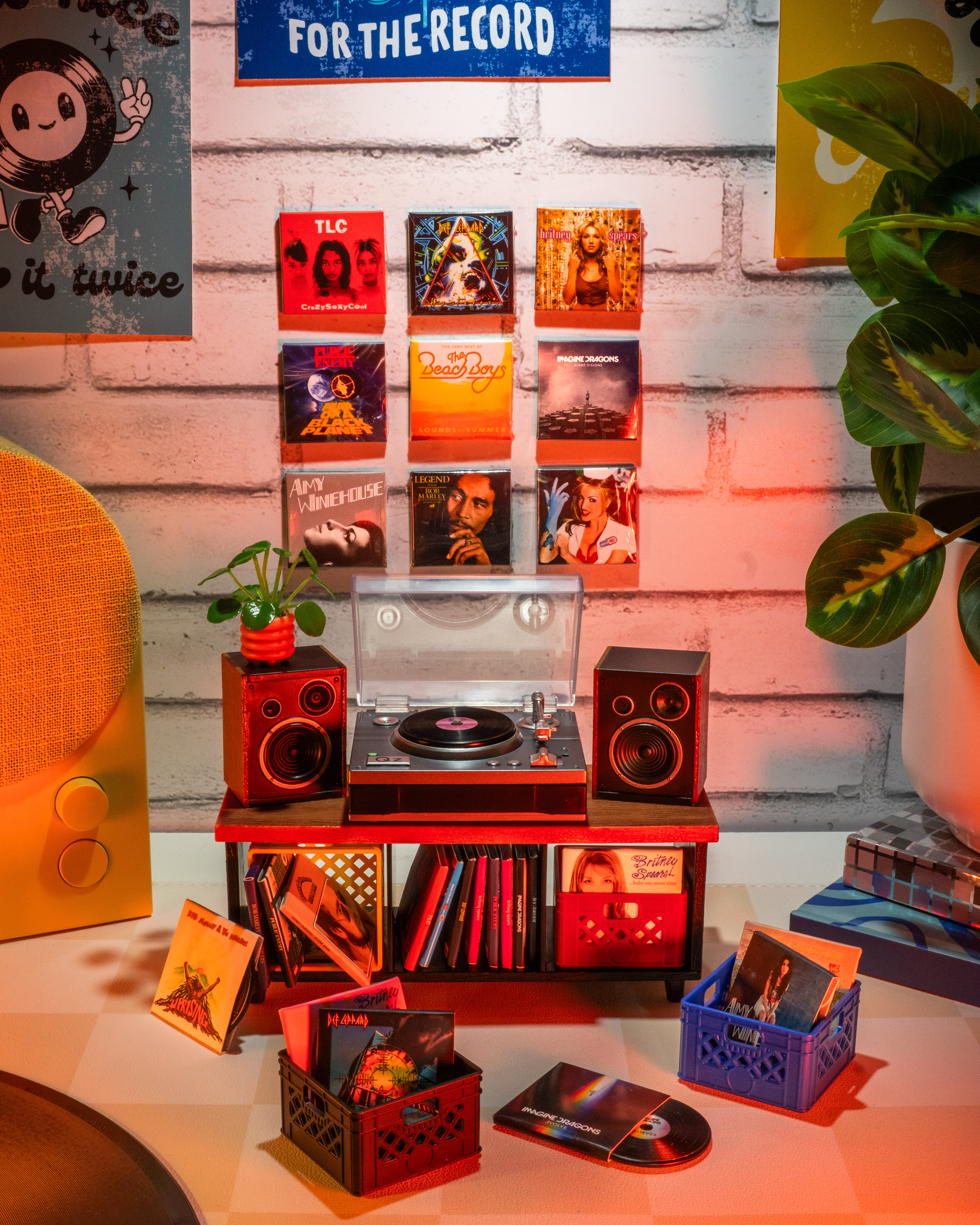 Miniverse Record player setup with vinyl records and speakers on a table against a wall with posters.