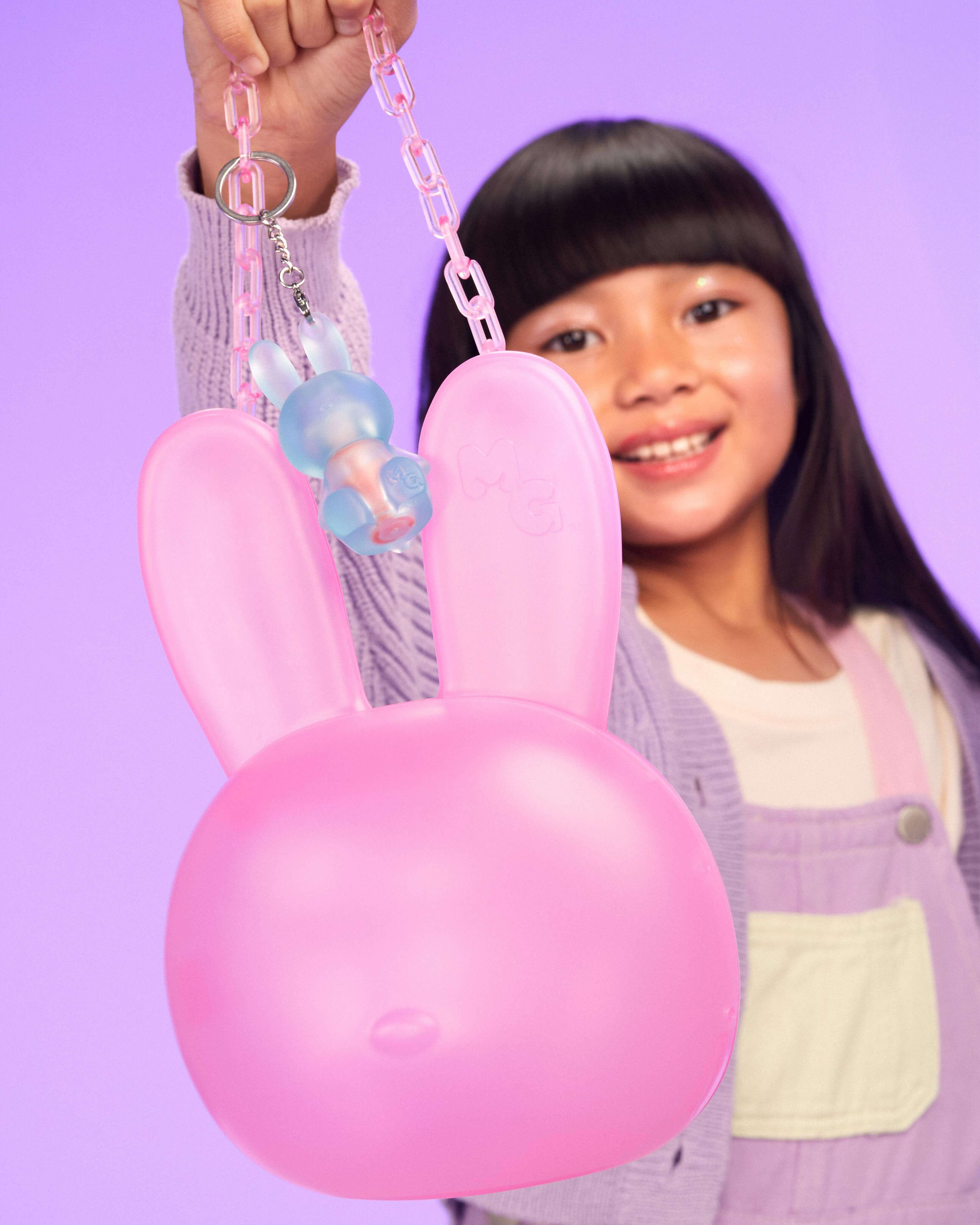 Child holding a pink bunny-shaped bag against a purple background