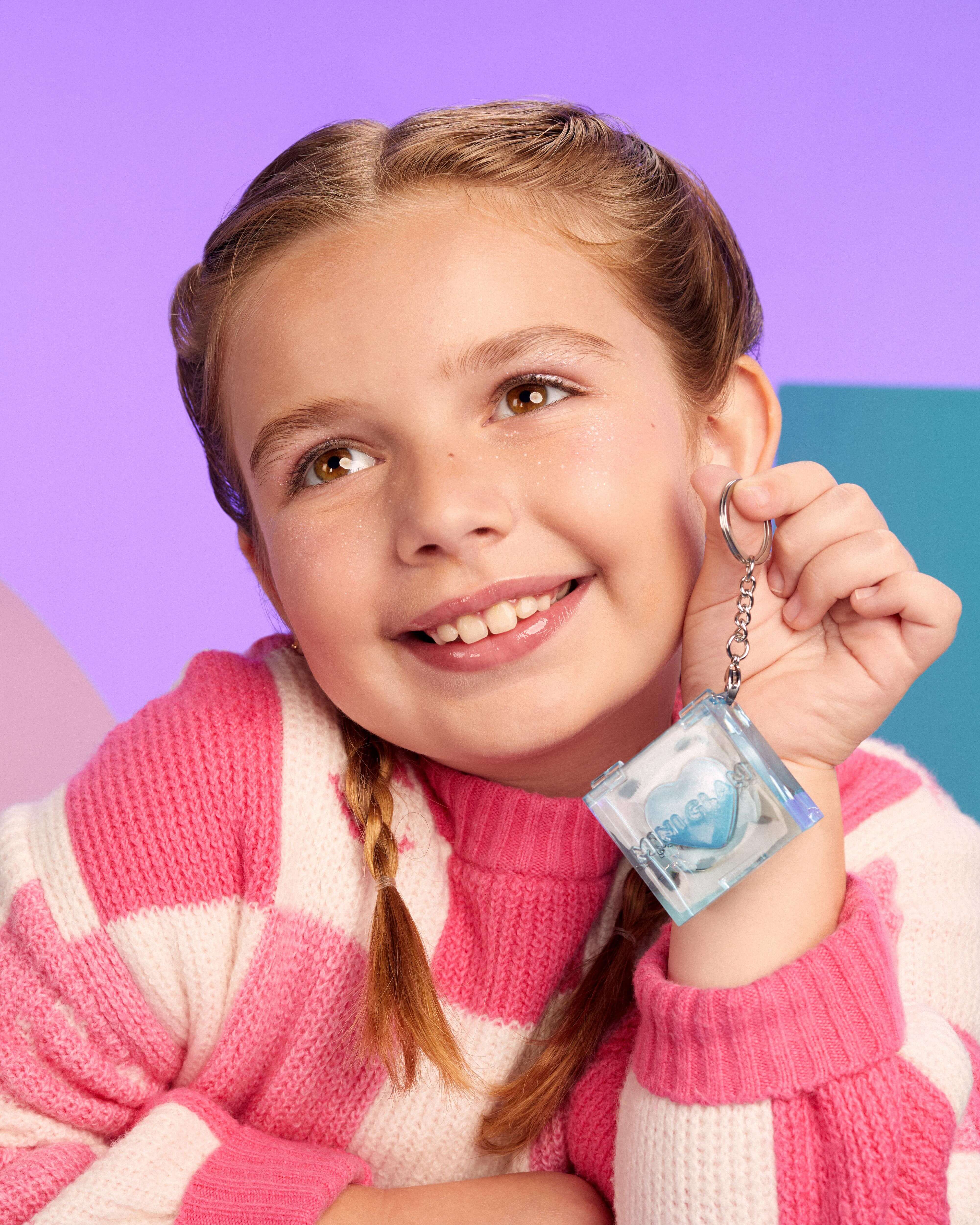 Young girl holding a Mini Glam shimmer with a colorful background