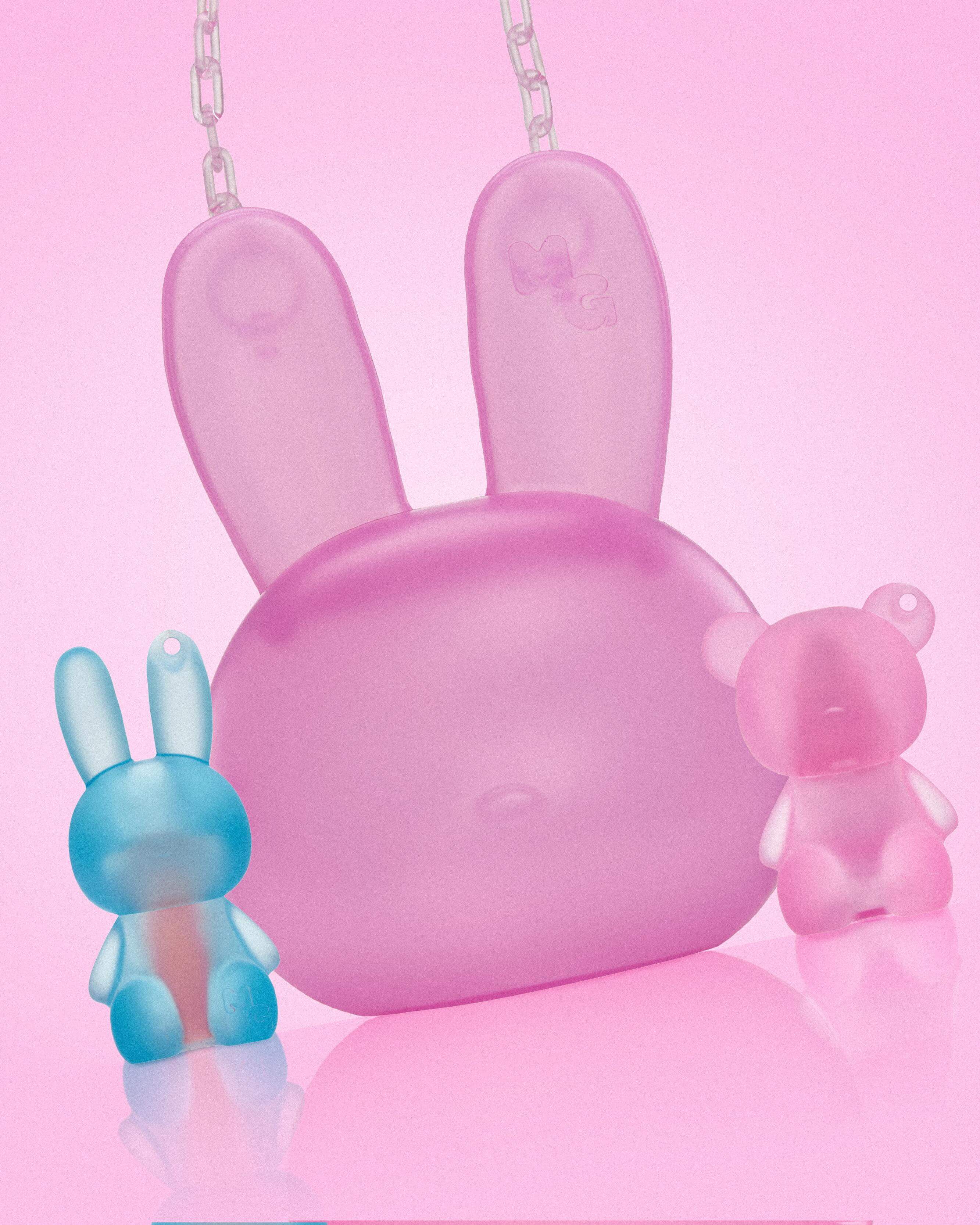 Pink rabbit-shaped Mini Glam purse with small rabbit and bear toys on a pink background