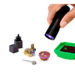 Hand holding a black flashlight with purple light on small Minecraft-style blocks and items.