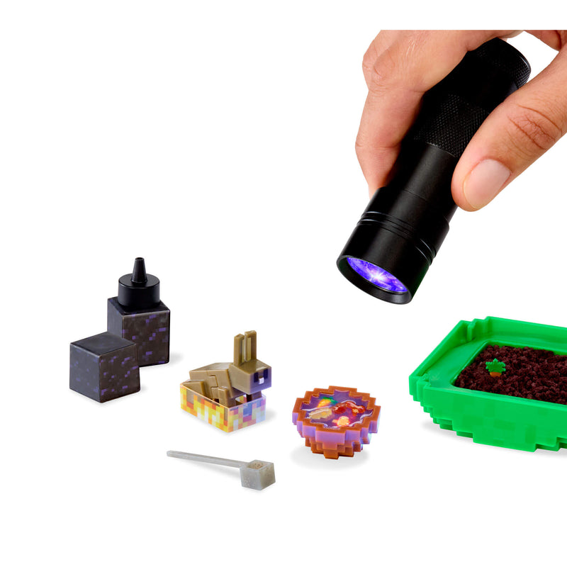 Hand holding a black flashlight with purple light on small Minecraft-style blocks and items.