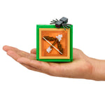 Small Minecraft-style spider in a green box held in a hand on a white background