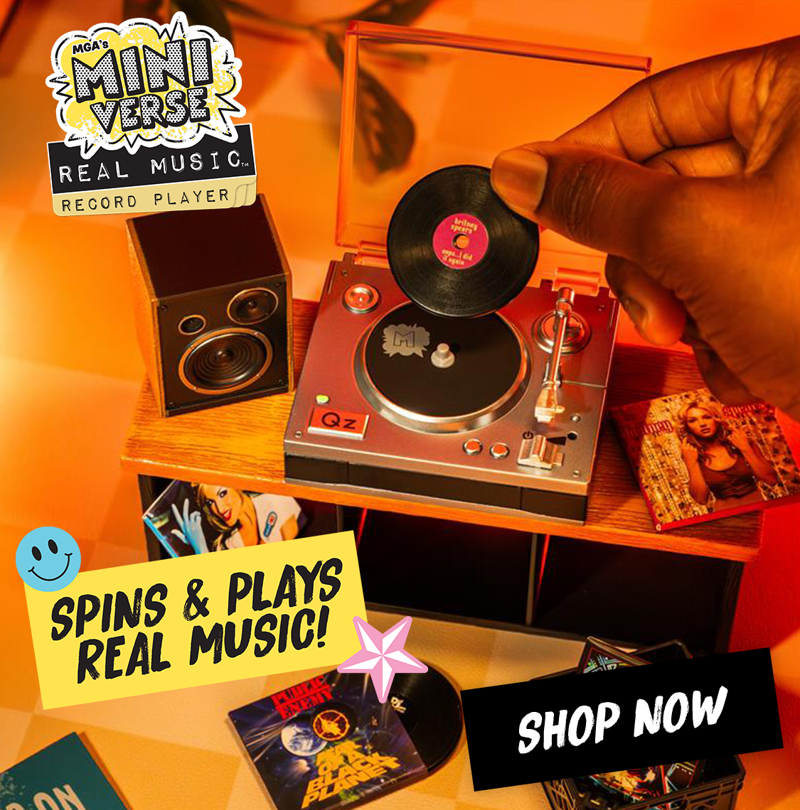 Miniature record player with a hand placing a vinyl record on it, surrounded by promotional text and branding. Shop Now call to action to shop the record player